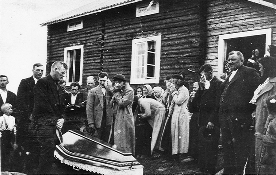Lainio 05 C.jpg -  Begravning av August Lantto, 1938. Elis Kruuka (Vighult), Klemon-Kalla med näsduk bakom kistan, Johan Esko framför dörröppningen, Ester Jakobsson längst till höger.